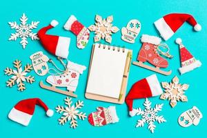 Top view of notebook with Christmas decorations and Santa hats on blue background. Happy holiday concept photo