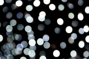 Bokeh white lights on black background. Abstract defocused many round light photo