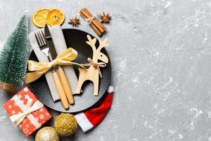 Top view of holiday dinner decorated with dried fruit and cinnamon on cement background. Set of plate, urensil and New Year decorations. Christmas time concept with epmty space for your design photo