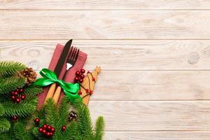 Top view of fork and knife on napkin with christmas decorations and new year tree on wooden background. Holiday and festive concept with copy space photo
