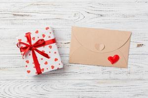 Envelope Mail with Red Heart and gift box over White Wooden Background. Valentine Day Card, Love or Wedding Greeting Concept photo