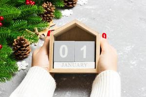 Top view of female hands holding a calendar on cement background. The first of January. Holiday decorations. New Year concept photo