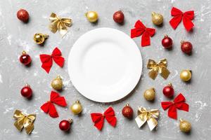 Top view of holiday dinner on cement background. Plate, baubles and bows. Christmas Eve concept photo