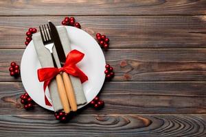 Top view of plate, fork and knife served on Christmas decorated wooden background. New Year Eve concept with copy space photo