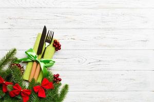 Top view of christmas decorations on wooden background. Fork and knife on napkin tied up with ribbon and empty space for your design. New year pattern concept photo