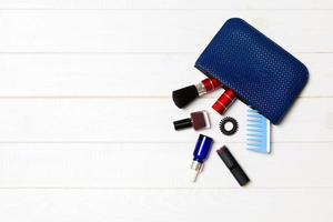 Make up products spilling out of cosmetics bag on white wooden background with empty space for your design photo