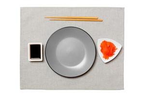 Empty round gray plate with chopsticks for sushi, ginger and soy sauce on grey napkin background. Top view with copy space for you design photo