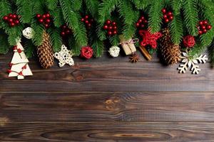 Top view of frame made of fir tree branches and holiday decorations on wooden background. Christmas concept with empty space for your design photo