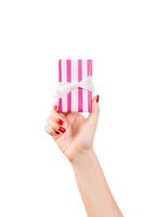 las manos de las mujeres dan Navidad envuelta u otro regalo hecho a mano en papel rosa con cinta blanca. aislado sobre fondo blanco, vista superior. concepto de caja de regalo de acción de gracias foto