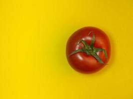 Tomato on colored paper. Greenhouse tomato on a yellow background. Bright vegetable background. photo