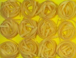Pasta nest on a yellow background. Noodle type. Culinary background. Background from noodles.Pasta on the table. Unprepared product.  Dough products photo