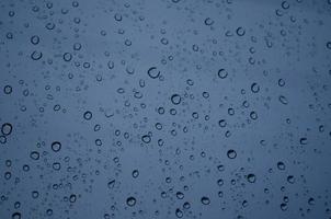 Blue rain drops on window. Sad and bad mood concept with gloomy colors. water drops on transparent background in a rainy days in night time. Stormy weather. isolation sad depression concept. photo