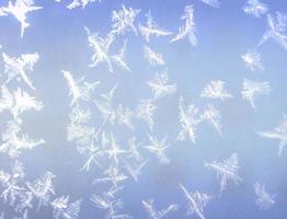 Snowflakes on window. Close-up photo of frost on glass. Hoarfrost ornaments. Beautiful rime close-up photo. Frost patterns on frozen window as a symbol of Christmas wonder.