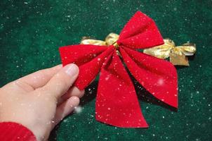 Bright red bow. Female hand holds toy for Christmas tree decoration. photo