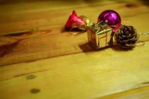 decoraciones temáticas de regalo de año nuevo y navidad sobre fondo de madera, que consisten en una caja de regalo dorada. bolas de colores brillantes piñas secas y campanas pequeñas espacio libre para el diseño foto