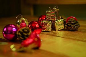 New Year and Christmas gift themed decorations on wooden background, consisting of a golden gift box.  shiny colored balls  Dried pine cones and small bells  free space for design photo