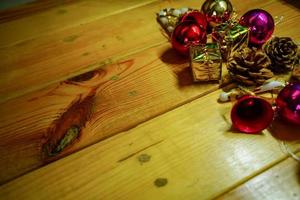 New Year and Christmas gift themed decorations on wooden background, consisting of a golden gift box.  shiny colored balls  Dried pine cones and small bells  free space for design photo