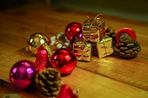 New Year and Christmas gift themed decorations on wooden background, consisting of a golden gift box.  shiny colored balls  Dried pine cones and small bells  free space for design photo