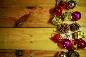 decoraciones temáticas de regalo de año nuevo y navidad sobre fondo de madera, que consisten en una caja de regalo dorada. bolas de colores brillantes piñas secas y campanas pequeñas espacio libre para el diseño foto