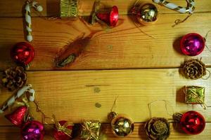 New Year and Christmas gift themed decorations on wooden background, consisting of a golden gift box.  shiny colored balls  Dried pine cones and small bells  free space for design photo