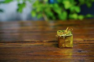 New Year and Christmas gift themed decorations on wooden background, consisting of a golden gift box.  shiny colored balls  Dried pine cones and small bells  free space for design photo