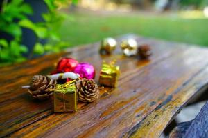 New Year and Christmas gift themed decorations on wooden background, consisting of a golden gift box.  shiny colored balls  Dried pine cones and small bells  free space for design photo