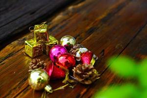 New Year and Christmas gift themed decorations on wooden background, consisting of a golden gift box.  shiny colored balls  Dried pine cones and small bells  free space for design photo