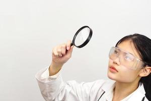 Young female scientist looking something through a magnifying glass. photo