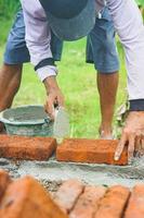 construction workers install bricks and cement from rows of bricks on exterior walls photo