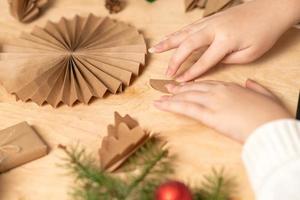 la niña hace decoraciones para árboles de navidad con papel con sus propias manos. instrucción paso a paso foto