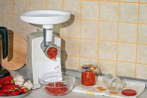 cocinar adjika de pimiento picante y ajo molido en una picadora de carne. preparativos para el invierno. remedio popular para la gripe y los resfriados foto