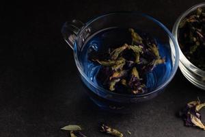 Butterfly pea flower tea in a clear glass on a black background. photo