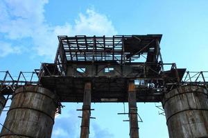 estructuras oxidadas tuberías de una antigua fábrica de acero industrial destruida y abandonada. las ruinas cubiertas de un área de construcción compleja. el concepto de quiebra y el cierre de la producción y puestos de trabajo foto