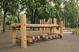 Rope bridge in outdoor modern children wooden playground in a public park of city. Eco-friendly lifestyle rest and childhood concept of safety environmentally infrastructure for kids. Funny adventure photo