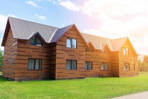 Two-storey wooden cottage with windows nature with a green lawn. Sale or purchase of new houses. A hotel for tourists. photo