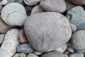 grandes piedras de diferentes formas en el primer plano de la orilla del río. hay muchas piedras pequeñas cerca. foto