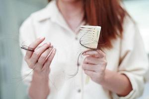 Asian woman have problem with long hair loss attach to comb brush. photo