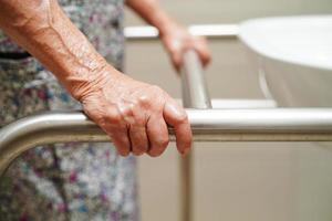 Asian elderly old woman patient use toilet support rail in bathroom, handrail safety grab bar, security in nursing hospital. photo