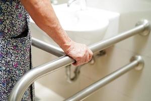 Asian elderly old woman patient use toilet support rail in bathroom, handrail safety grab bar, security in nursing hospital. photo