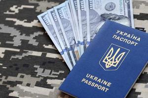 Ukrainian foreign passport on fabric with texture of military pixeled camouflage. Cloth with camo pattern in grey, brown and green pixel shapes and Ukrainian ID photo