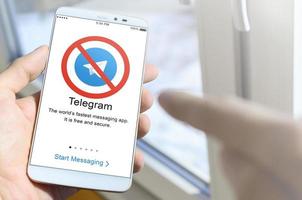 KHARKOV, UKRAINE - APRIL 27, 2022 A mobile phone with the Telegram app screen with a prohibiting sign. Roskomnadzor blocked the Telegram service in Russia. Access to telegram messenger is closed photo