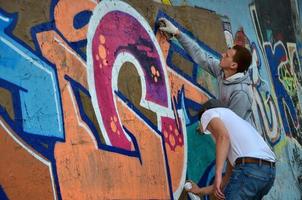 KHARKOV. UKRAINE - MAY 2, 2022 Festival of street arts. Young guys draw graffiti on an old concrete walls in the center of the city. The process of painting on walls with aerosol spray cans photo