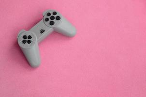 Playing games concept. Single pad joystick lies on the blanket of furry pink fleece fabric. Controller for video games on a background texture of light pink soft plush fleece material photo