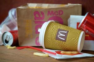 KHARKOV, UKRAINE - MAY 12, 2022 McDonald's garbage or disposable trash on dark brown wooden background photo