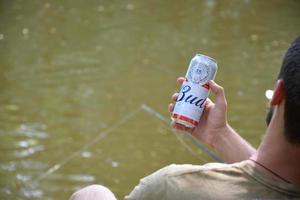 KHARKOV. UKRAINE - MAY 17, 2022 Man holds Budweiser Lager Alcohol Beer during fishing. Budweiser is Brand from Anheuser-Busch Inbev most popular in America photo