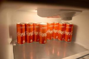 KHARKOV. UKRAINE - MAY 2, 2022 Coca-cola red soda drink cans inside domestic cooler fridge photo