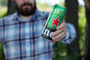 KHARKOV. UKRAINE - MAY 2, 2022 Man with green tin can of Heineken lager beer produced by the Dutch brewing company Heineken N.V. photo