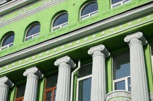 Restored old multi-storey building with antique columns, painted in green photo