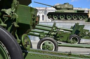 Photo of three guns of the Soviet Union of the Second World War against the background of the green tank T-34