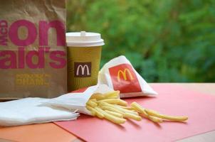 KHARKOV, UKRAINE - MAY 12, 2022 McDonald's take away paper bag and junk food on wooden table outdoors photo